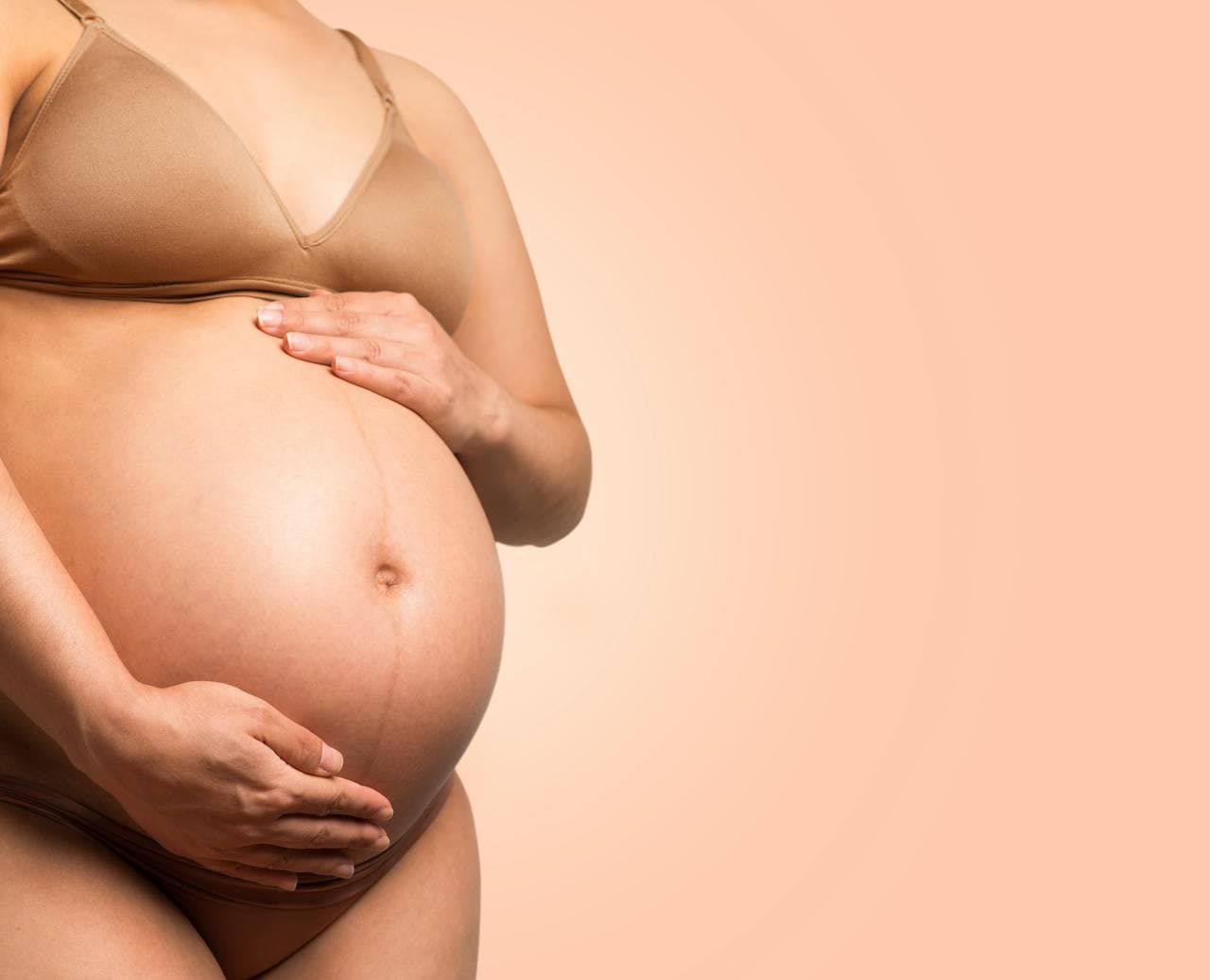 Mulher grávida com as mãos na barriga